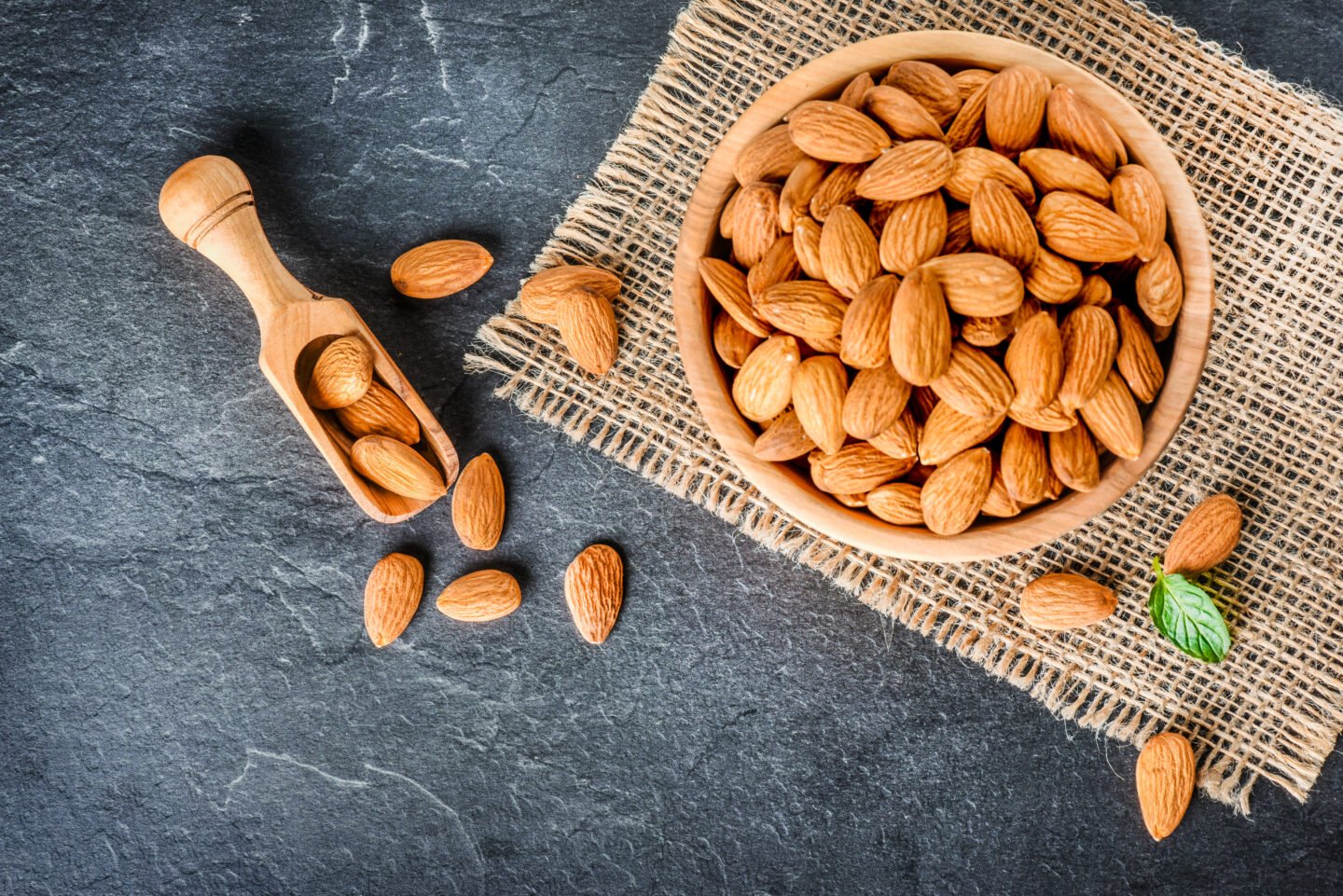 Top,View,Of,Almonds,On,Dark,Stone,Table,With,Wood