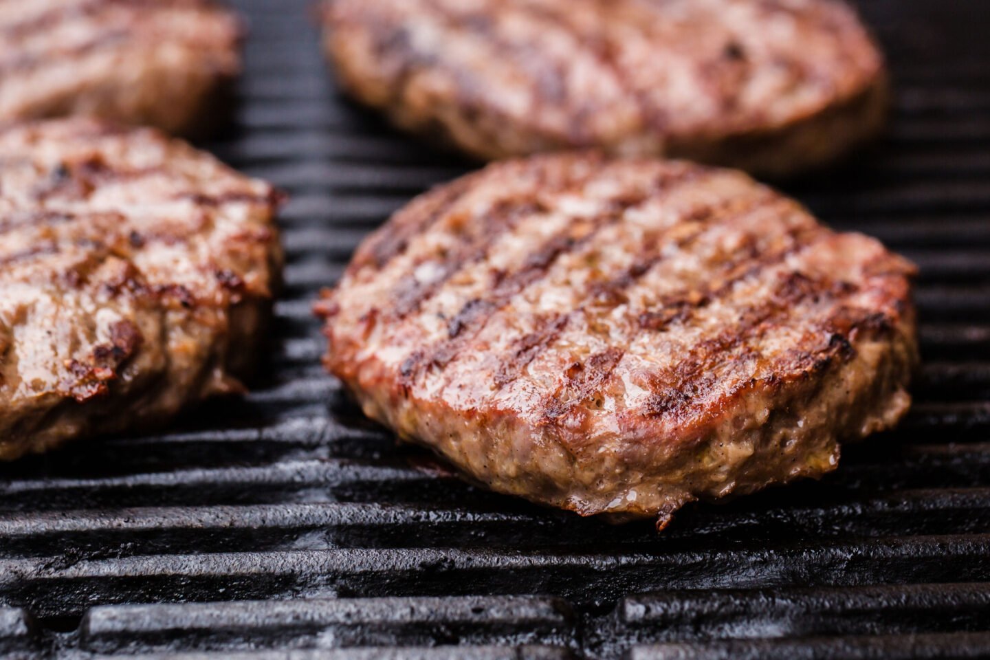 beef patties cooking on a grill
