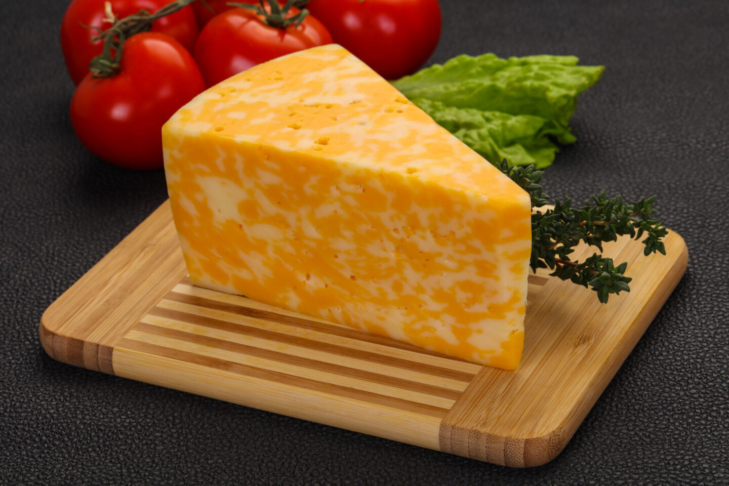 cheddar jack cheese block on wooden cutting board