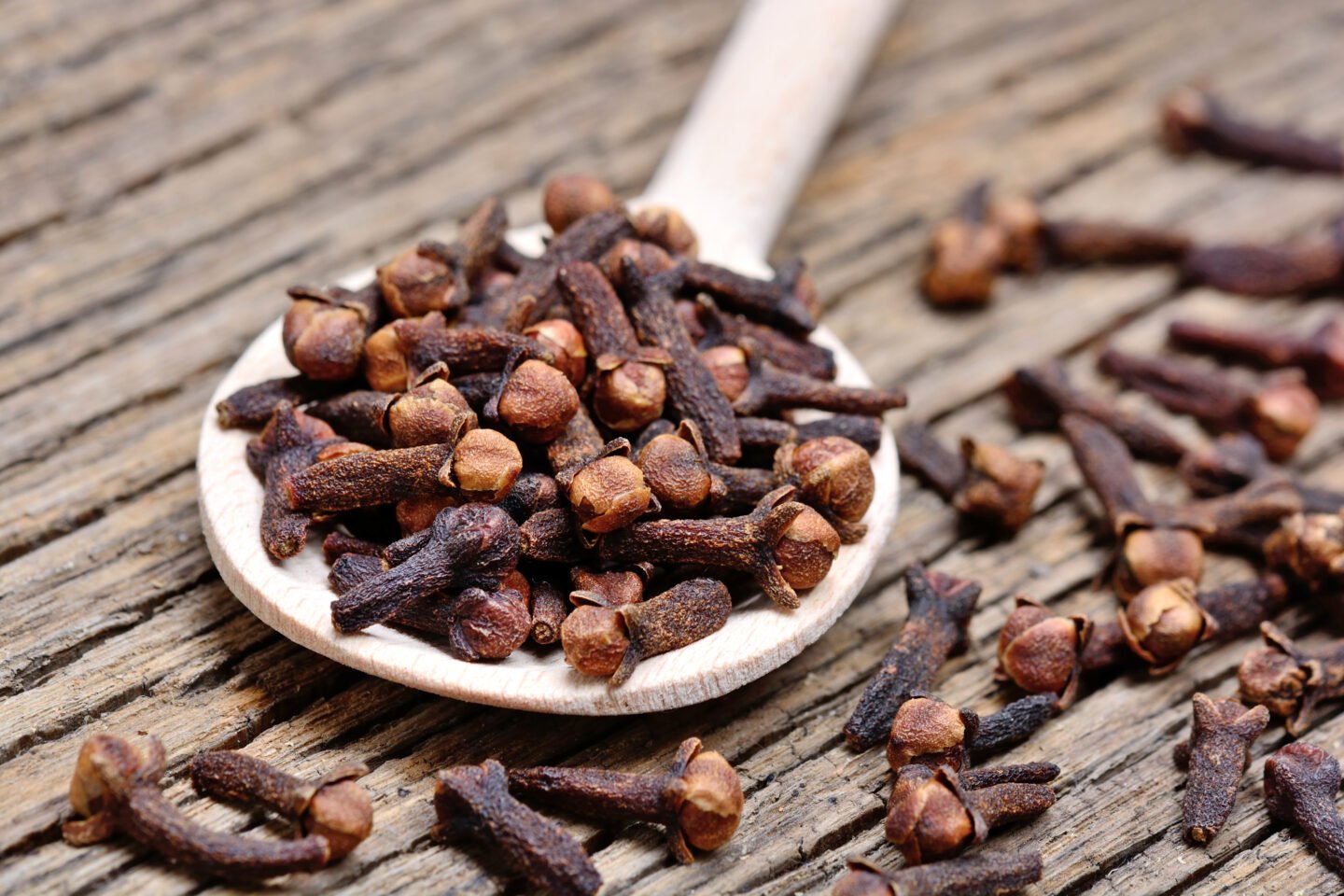 Wooden,Spoon,With,Cloves,On,Rustic,Table