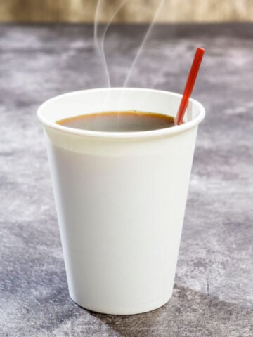 coffee in styrofoam cup with stirrer on marble countertop
