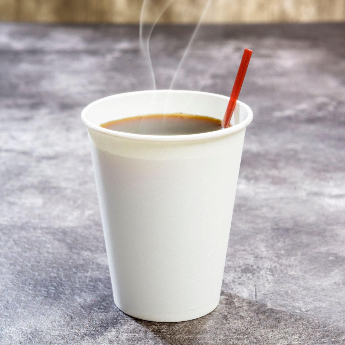 coffee in styrofoam cup with stirrer on marble countertop