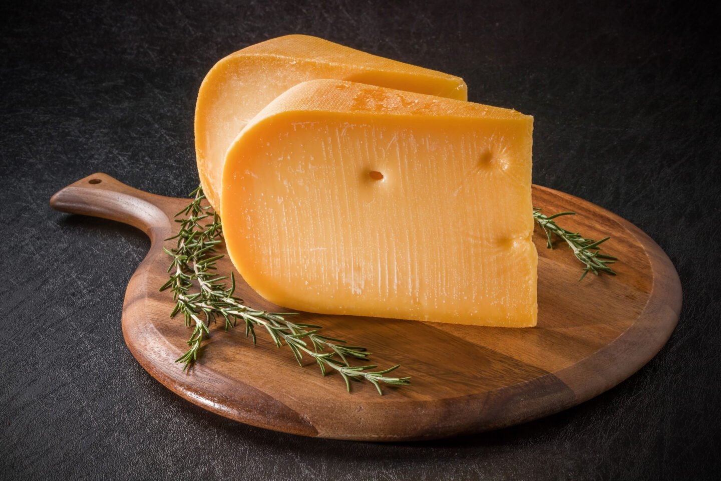 gouda cheese block on wooden chopping board
