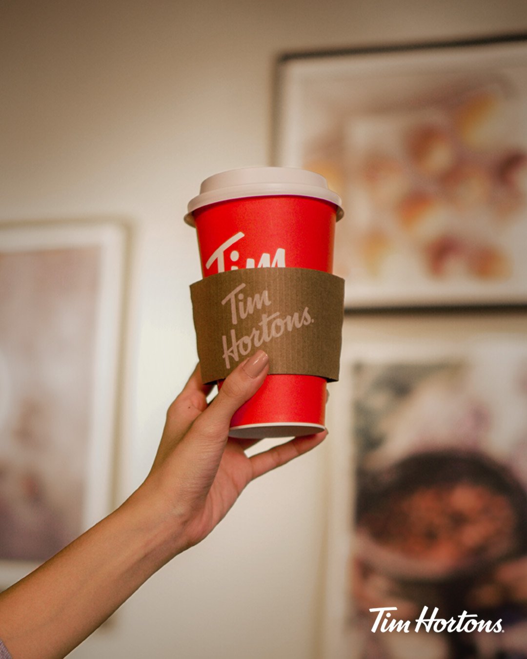 hand holding up tim hortons takeaway cup with holder
