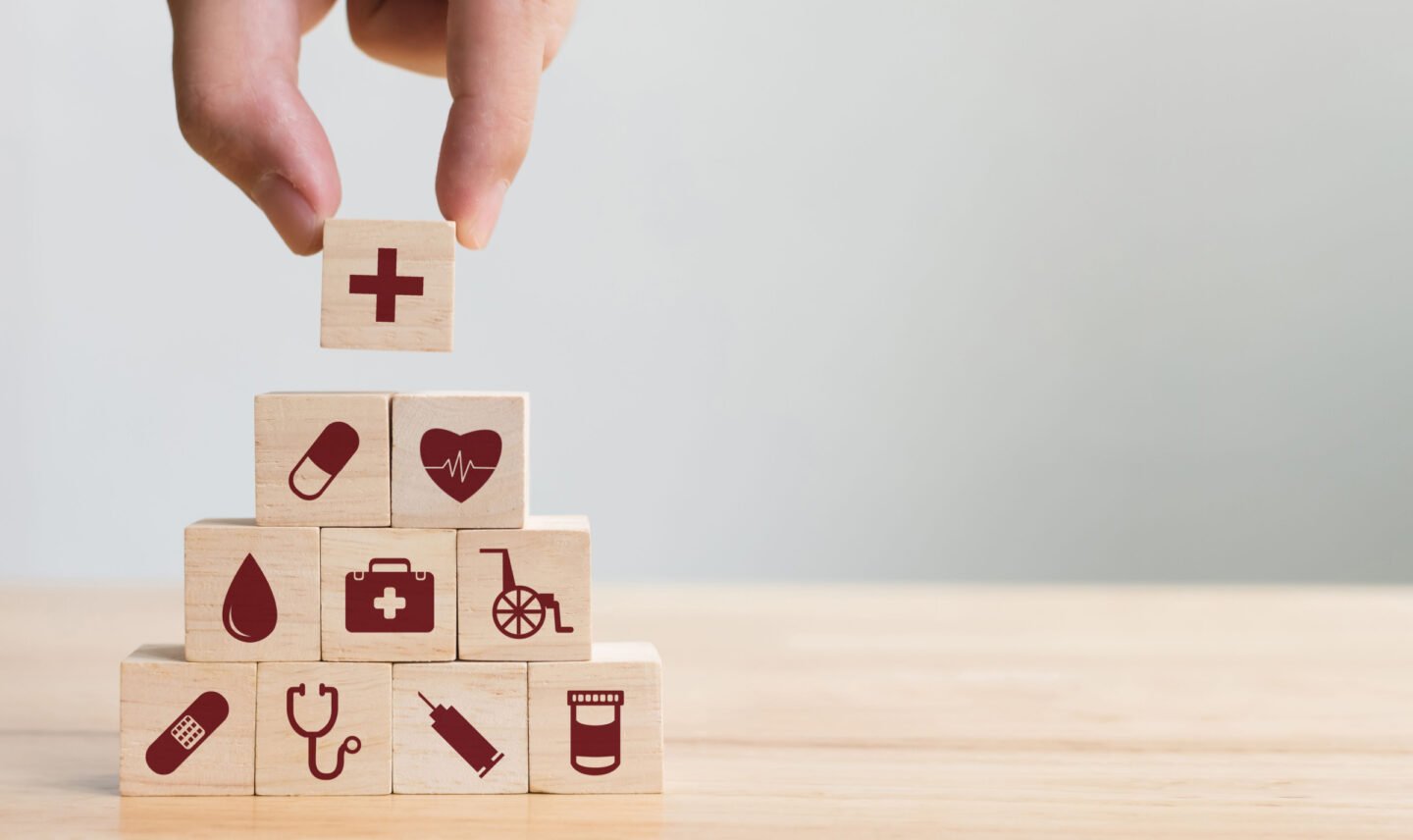 hand stacking wooden blocks printed with medical icons