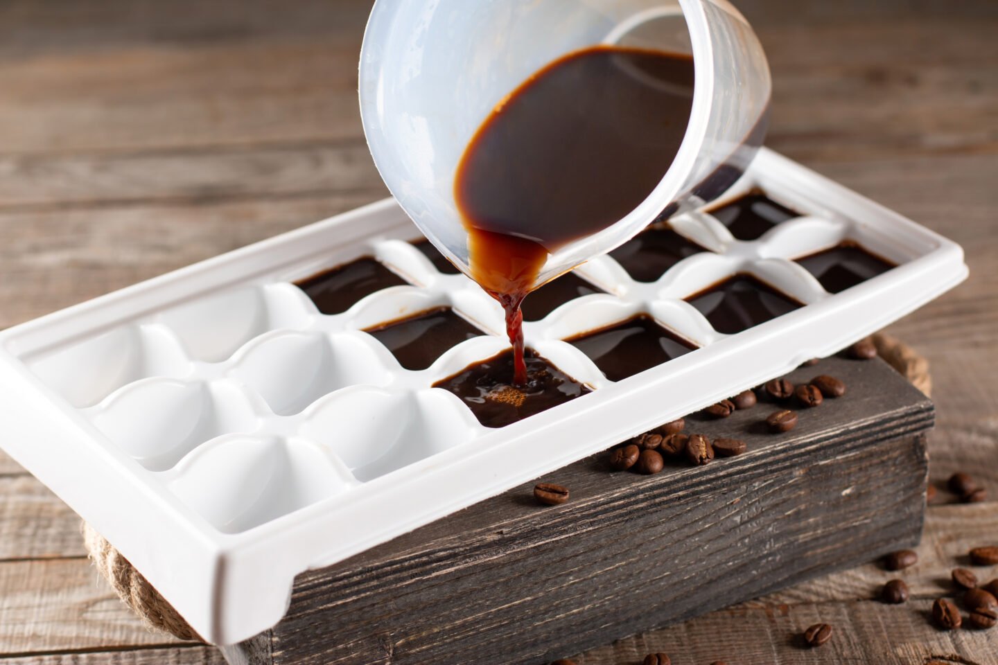 Pouring,Coffee,In,Ice,Cube,Tray,On,A,Wooden,Table