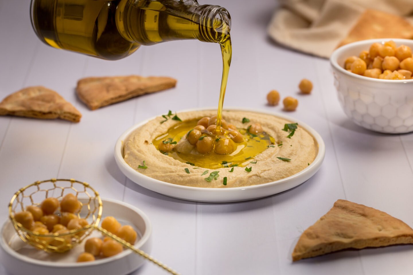 Pouring,Olive,Oil,On,Hummus,Plate