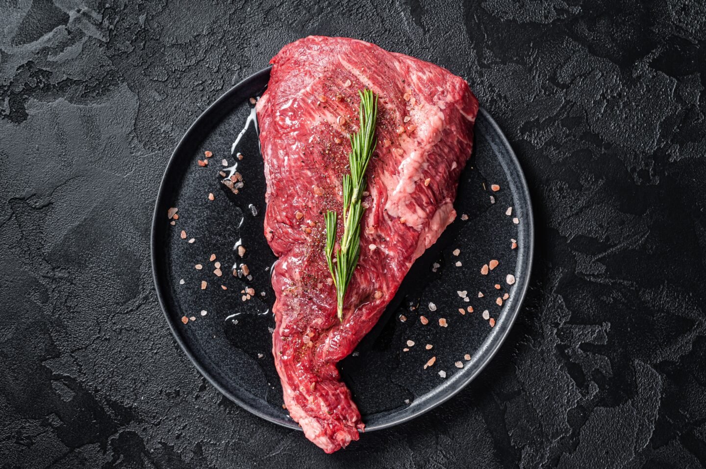 Seasoned,Raw,Tri tip,Beef,Meat,Steak,On,Plate.,Black,Background.