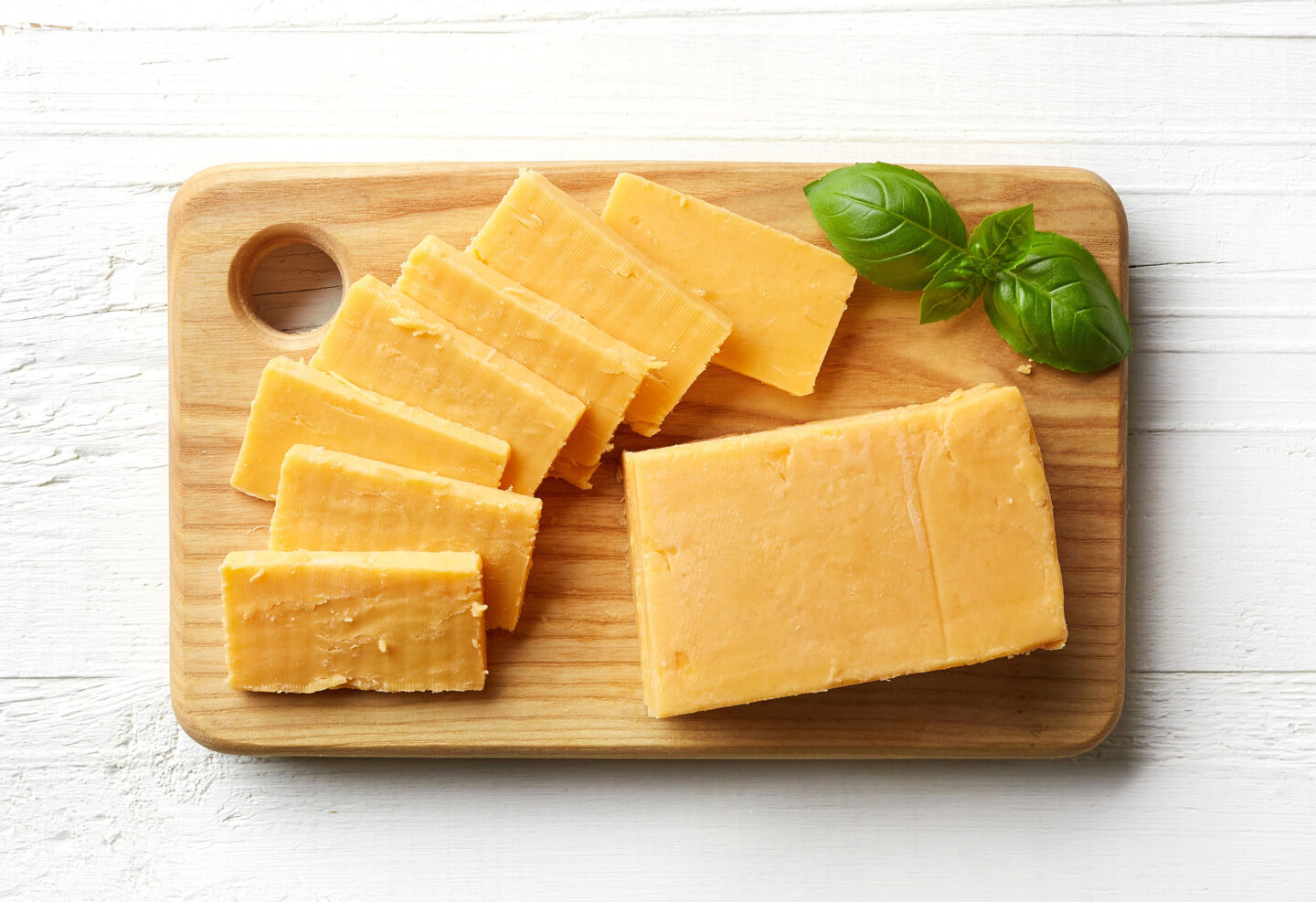 sliced cheddar cheese on wooden cutting board