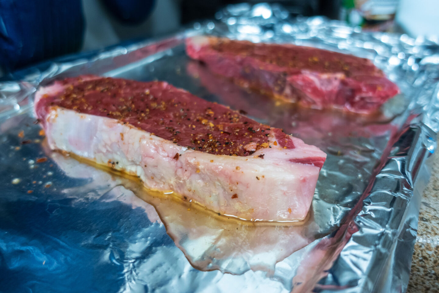 steaks laying on aluminum foil on baking sheet