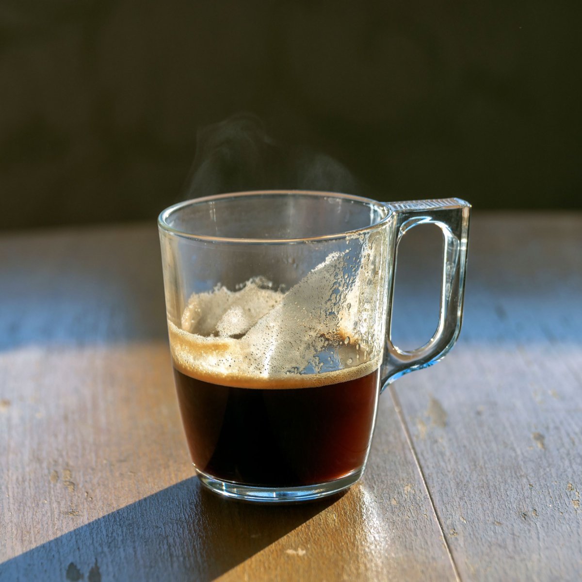 unfinished coffee in glass mug on wooden table