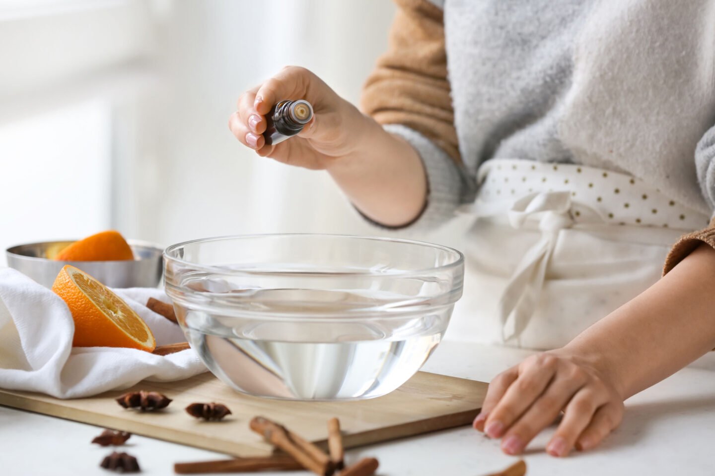 woman adding extract or essential oil to bowl of water