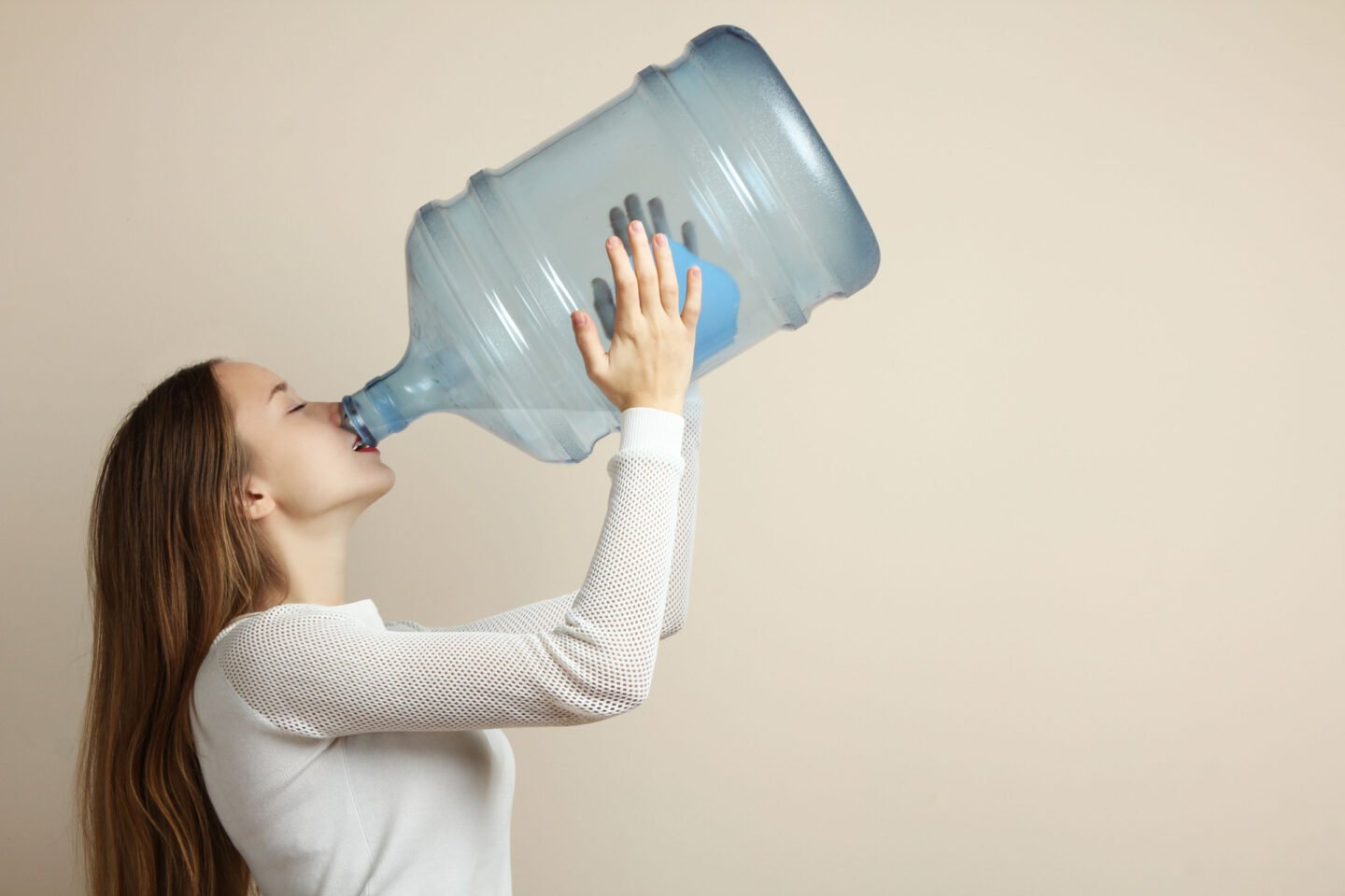 woman drinking from large water bottle