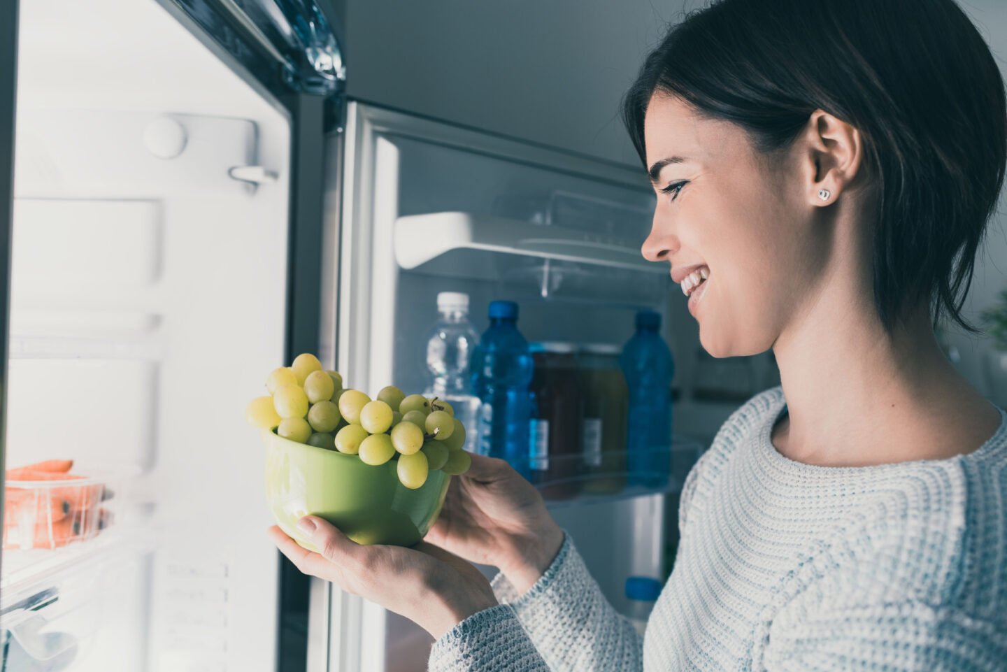 woman putting grapes into fridge