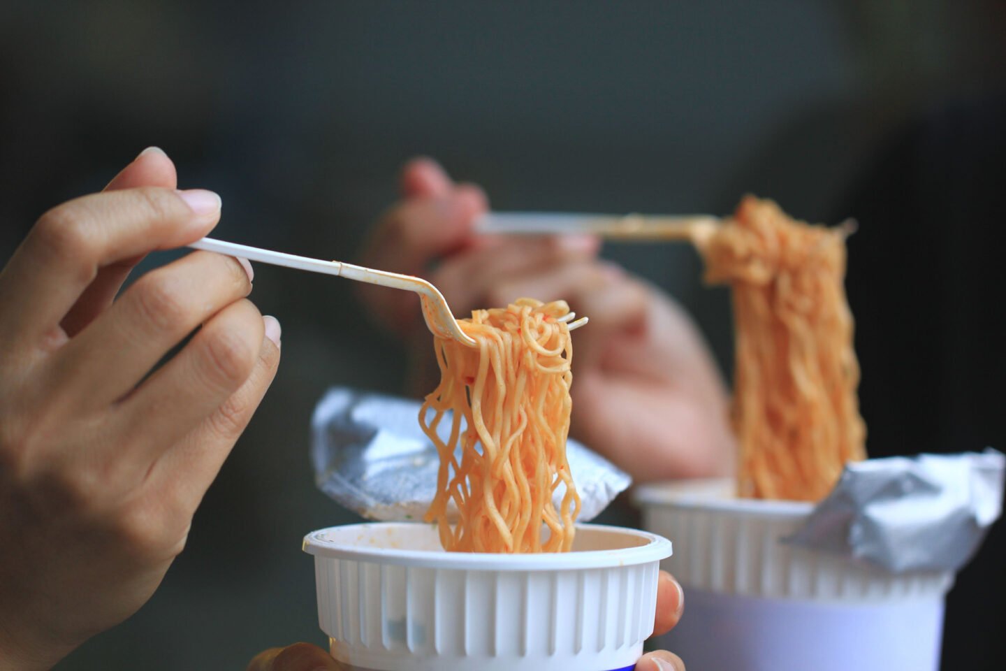 women eating instant noodles in cups