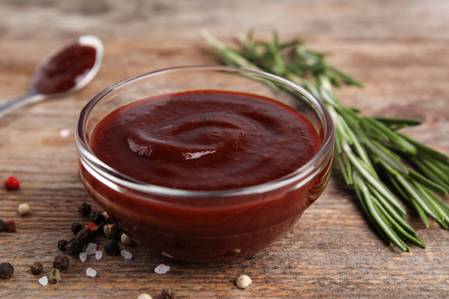 bowl of bbq sauce with peppercorns and rosemary