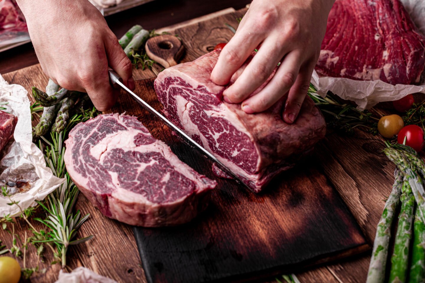 butcher slicing fresh ribeye steaks