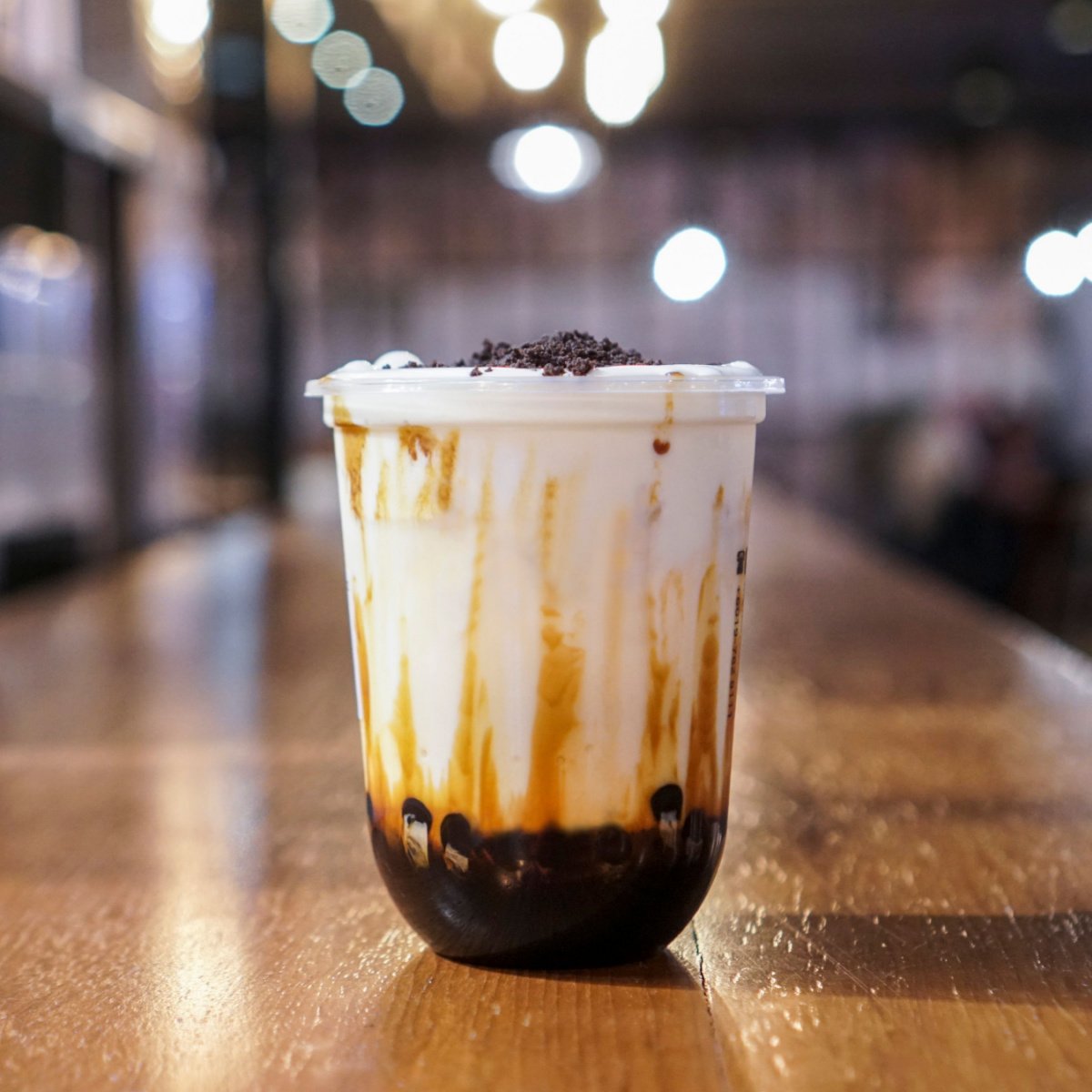 cup of boba bubble tea topped on wooden table