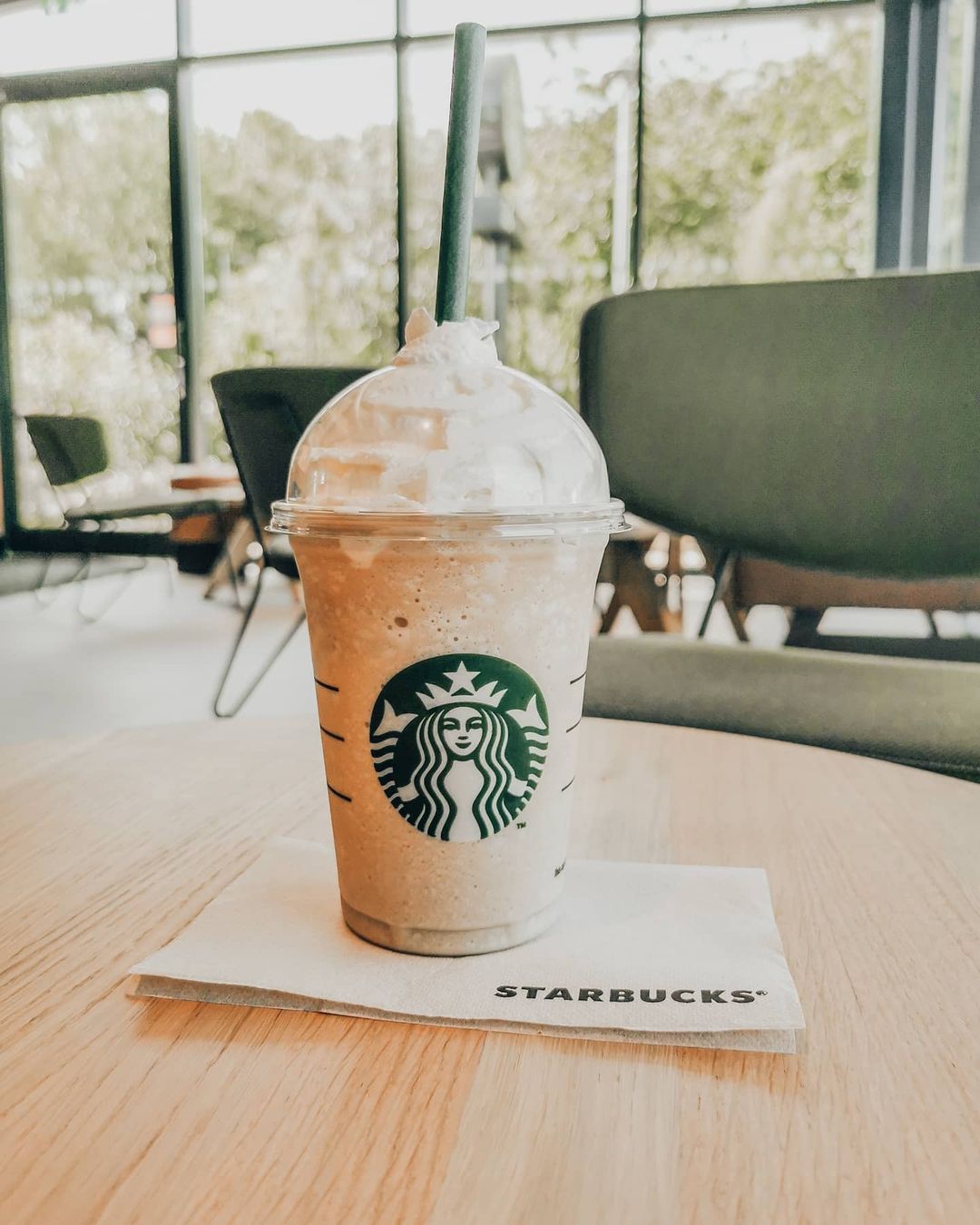 cup of starbucks coffee frappuccino on wooden table on top of napkin