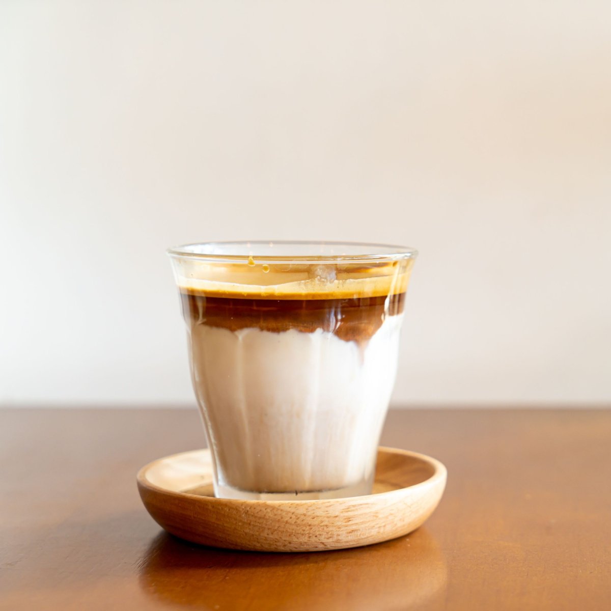 glass of dirty coffee on wooden saucer