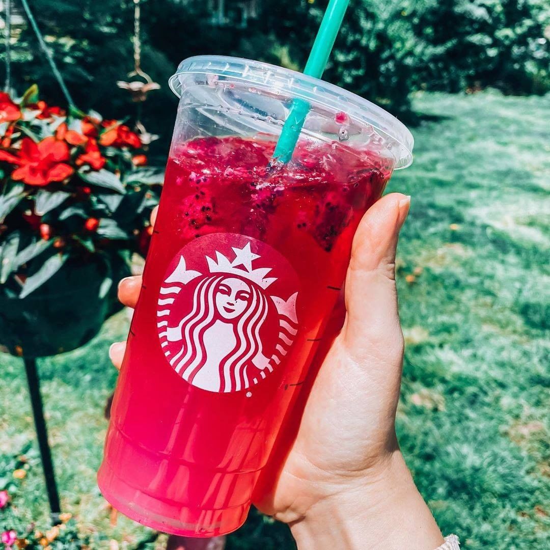 hand holding cup of mango dragonfruit lemonade starbucks refresher