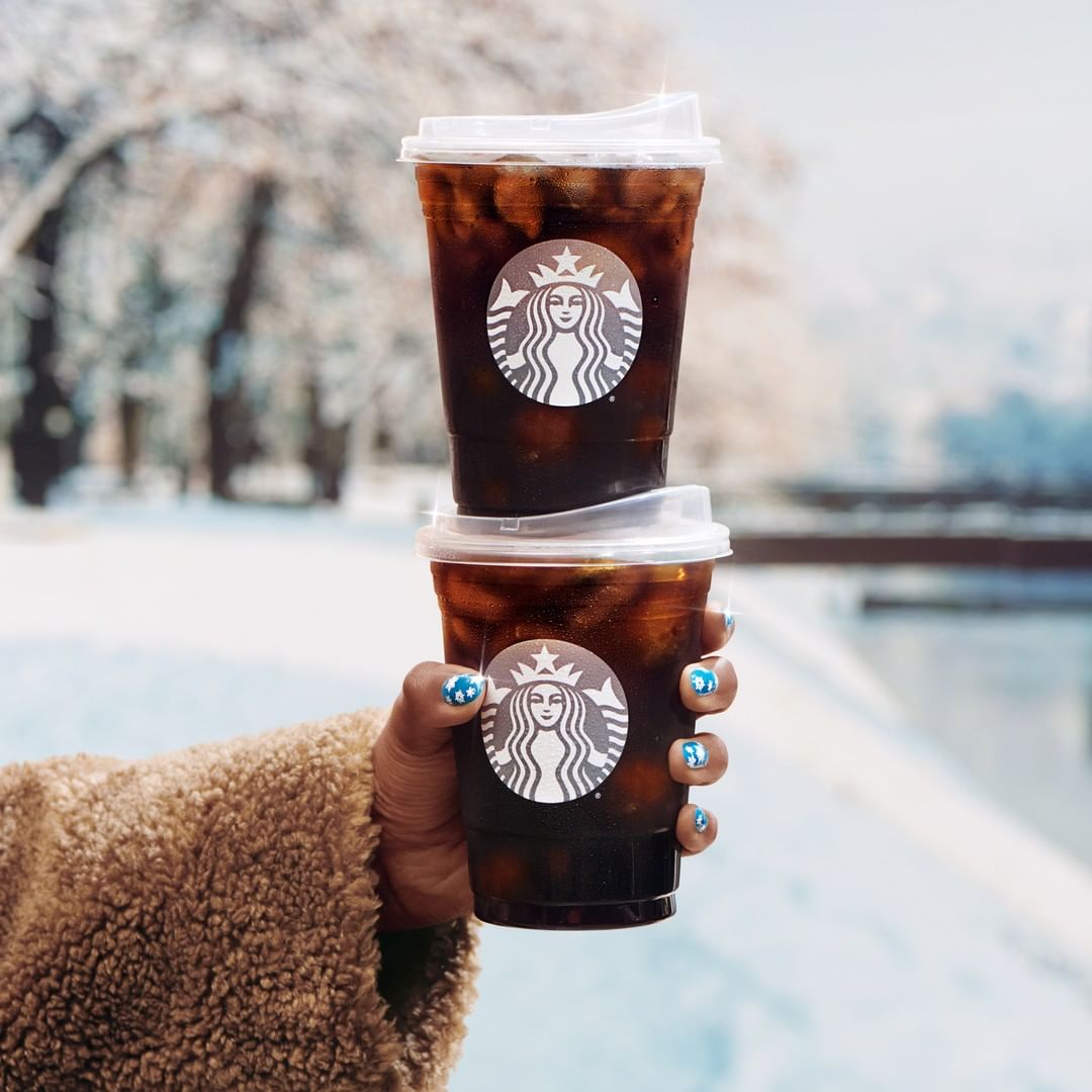 hand holding cups of starbucks cold brew coffee stacked on one another