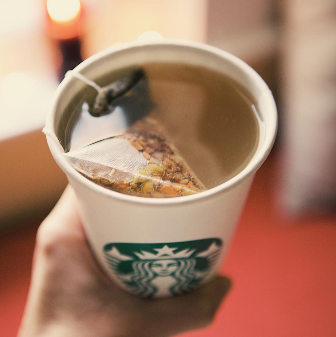 hand holding starbucks disposable cup containing tea lemonade and honey