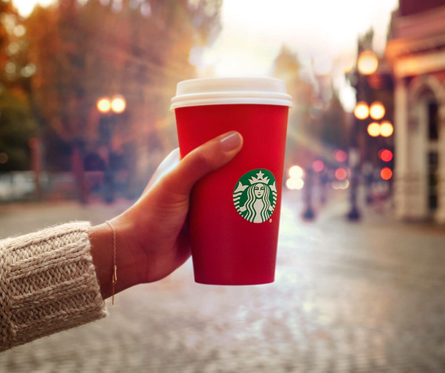 hand holding starbucks red christmas cup to light