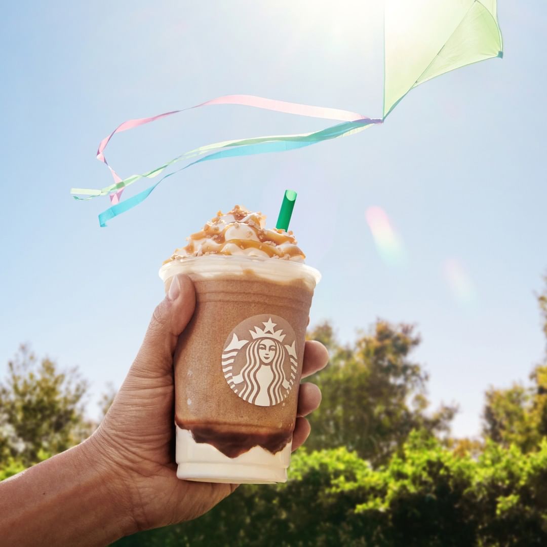 hand holding up cup of starbucks caramel ribbon crunch creme frappuccino
