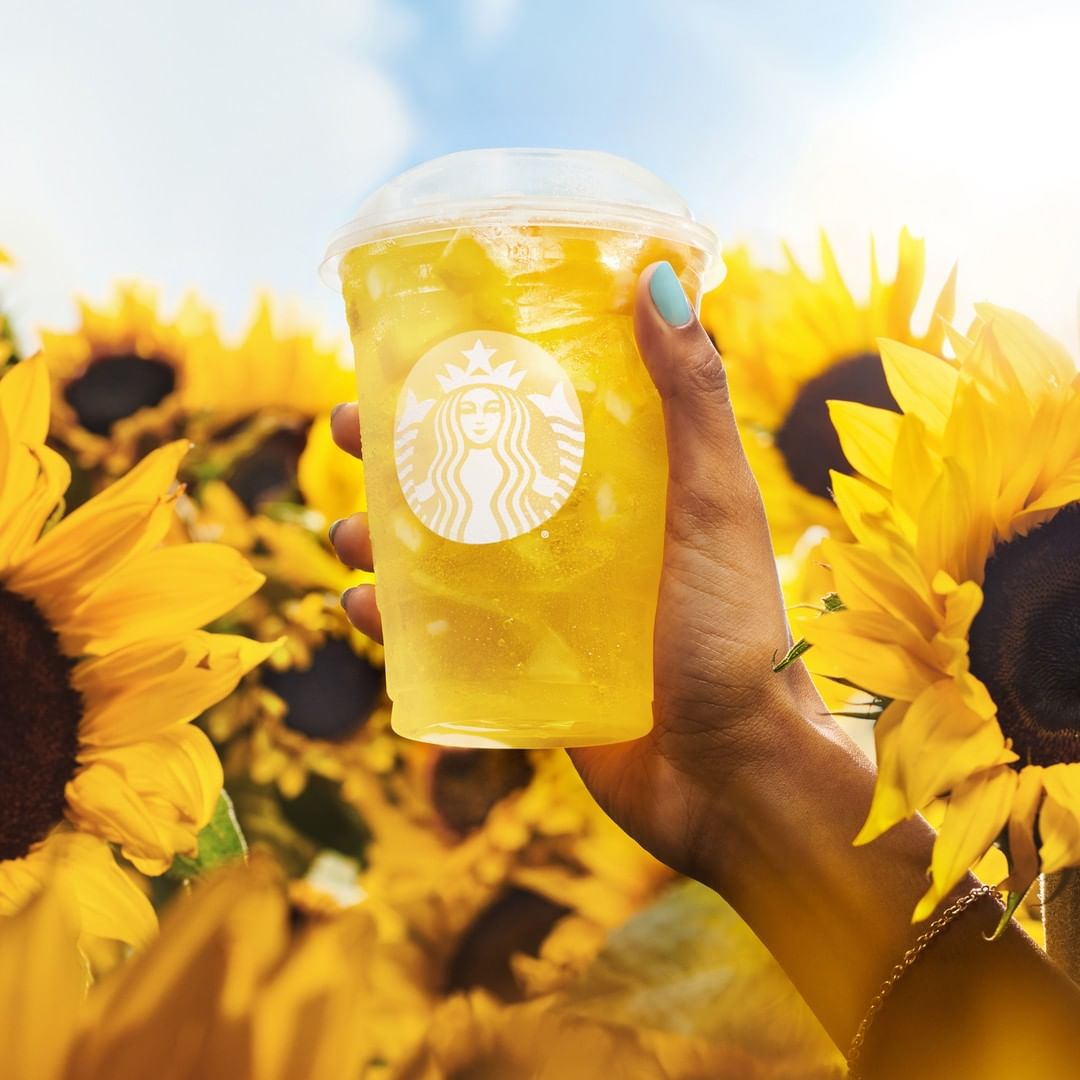 hand holding up cup of starbucks pineapple passionfruit refresher