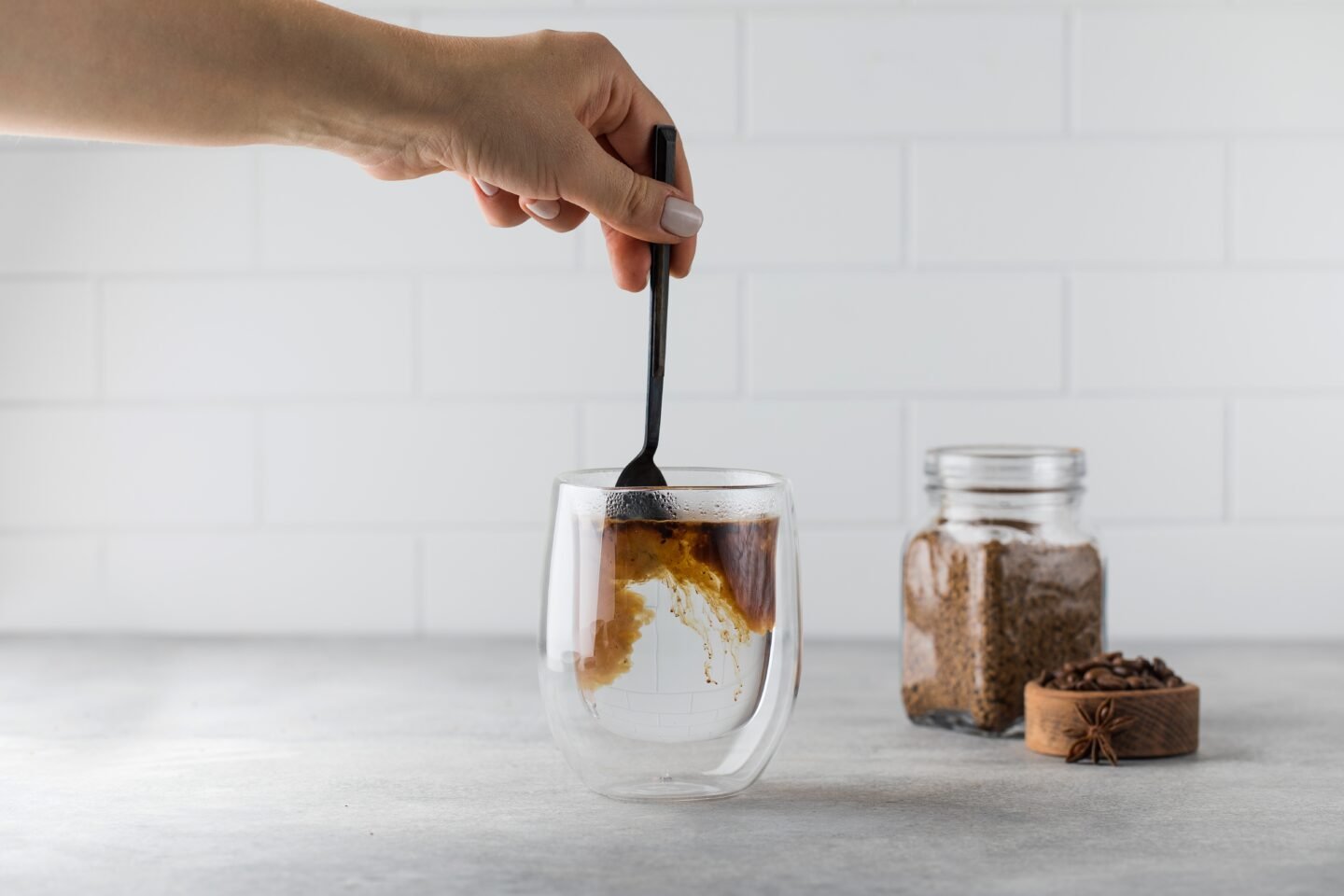 Woman,Stirs,Instant,Coffee,In,Glass,Mug,With,Boiled,Water