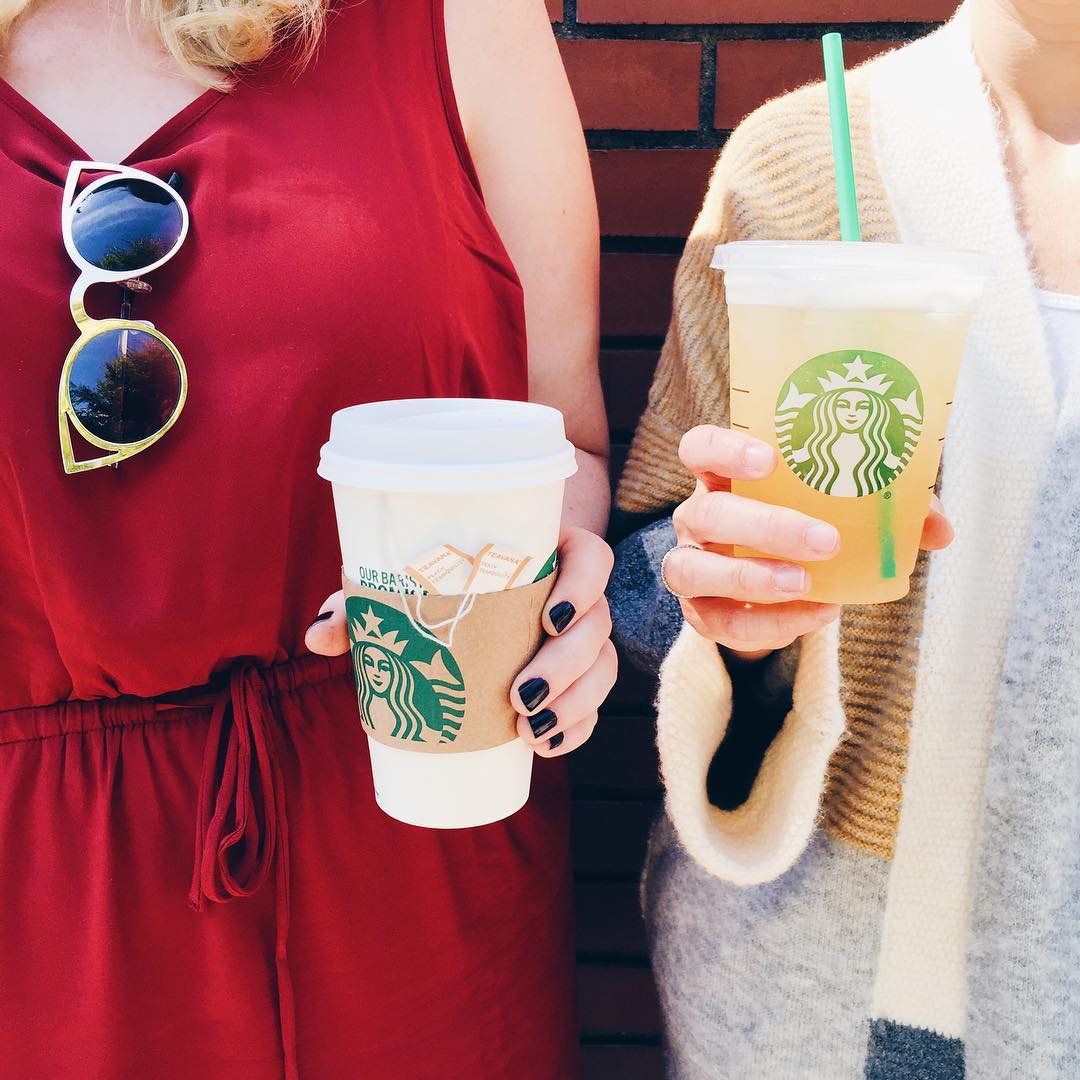 hands holding cups of starbucks hot and iced peach tranquility tea