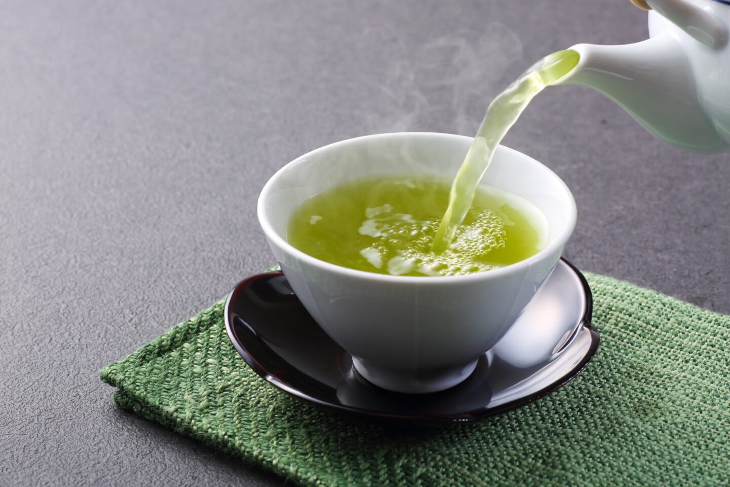 Green tea is poured into a white tea cup