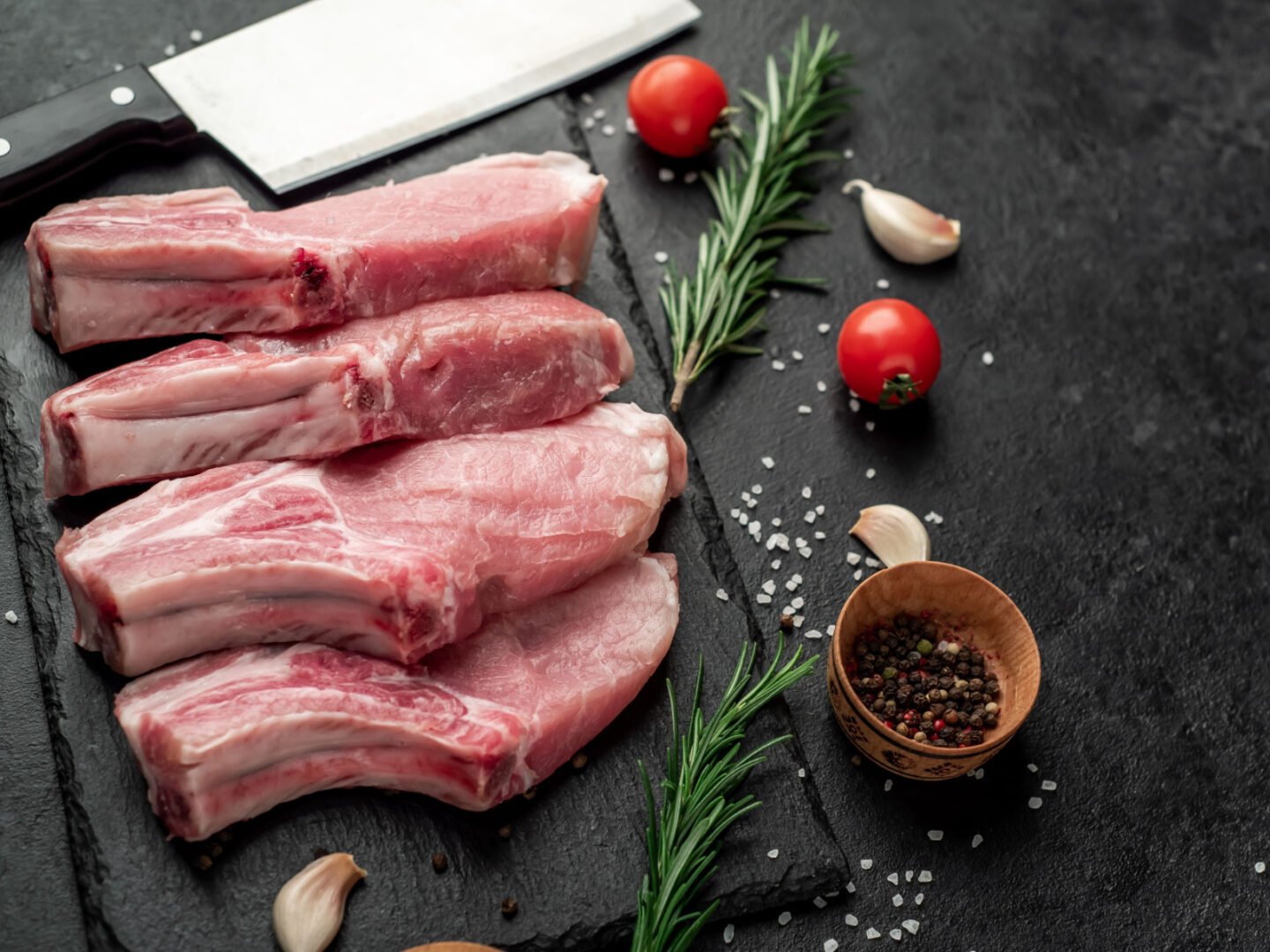 raw pork steaks on stone slab