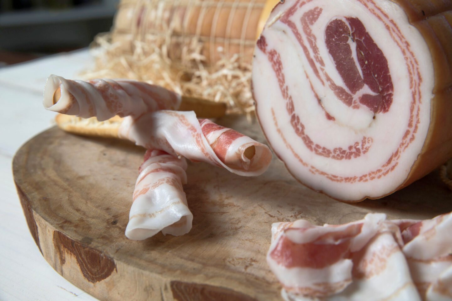 rolls of italian pancetta on chopping board