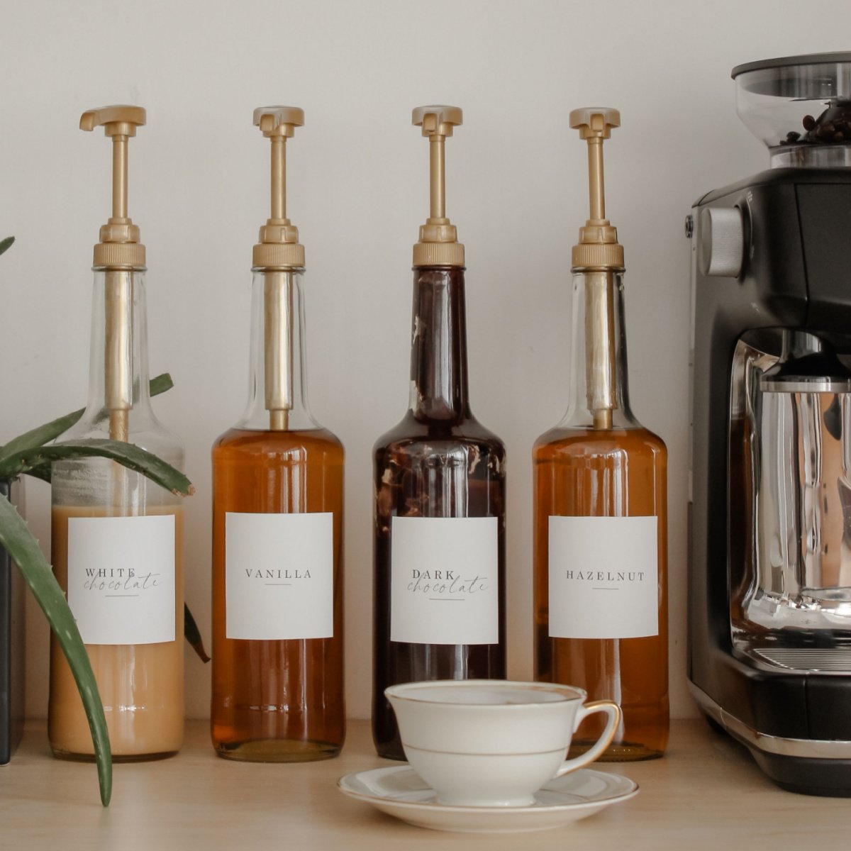 row of coffee syrup pumps beside coffee maker and cup