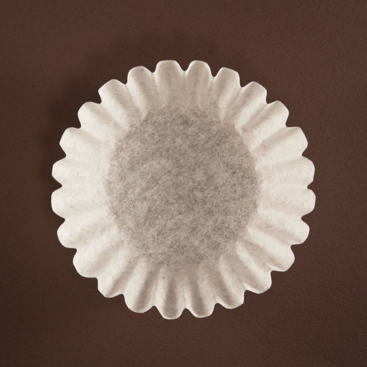 single paper coffee filter on brown surface