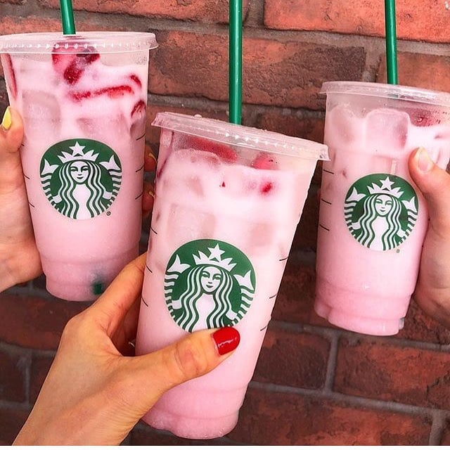 three hands holding cups of starbucks iced pink drinks