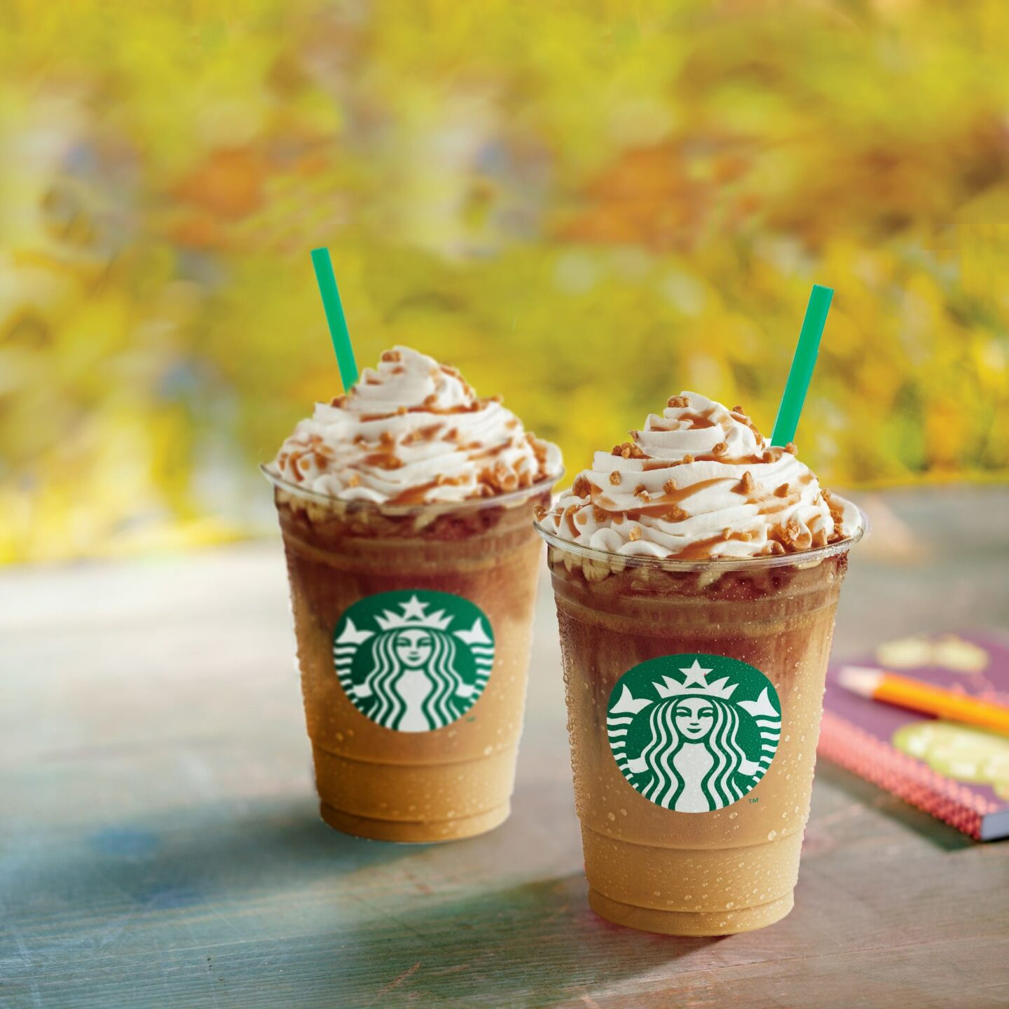 two cups of starbucks caramel ribbon crunch frappuccino on wooden table