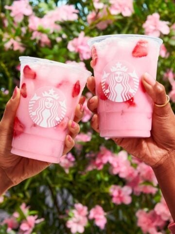 Two Female Hands Each Holding Up Cups Of Starbucks Pink Drink 360x480