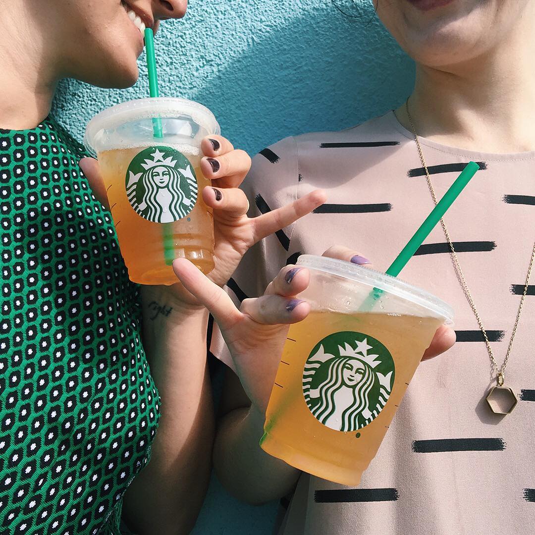 two smiling women holding cups of starbucks iced tea