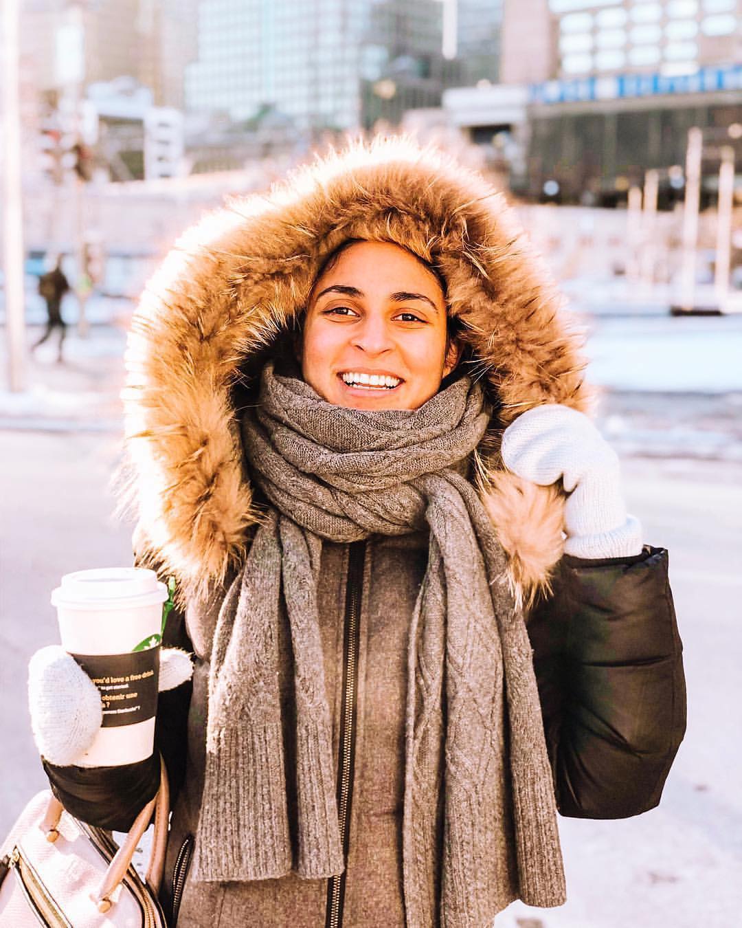 woman holding cup of starbucks hot chocolate while smiling at camera