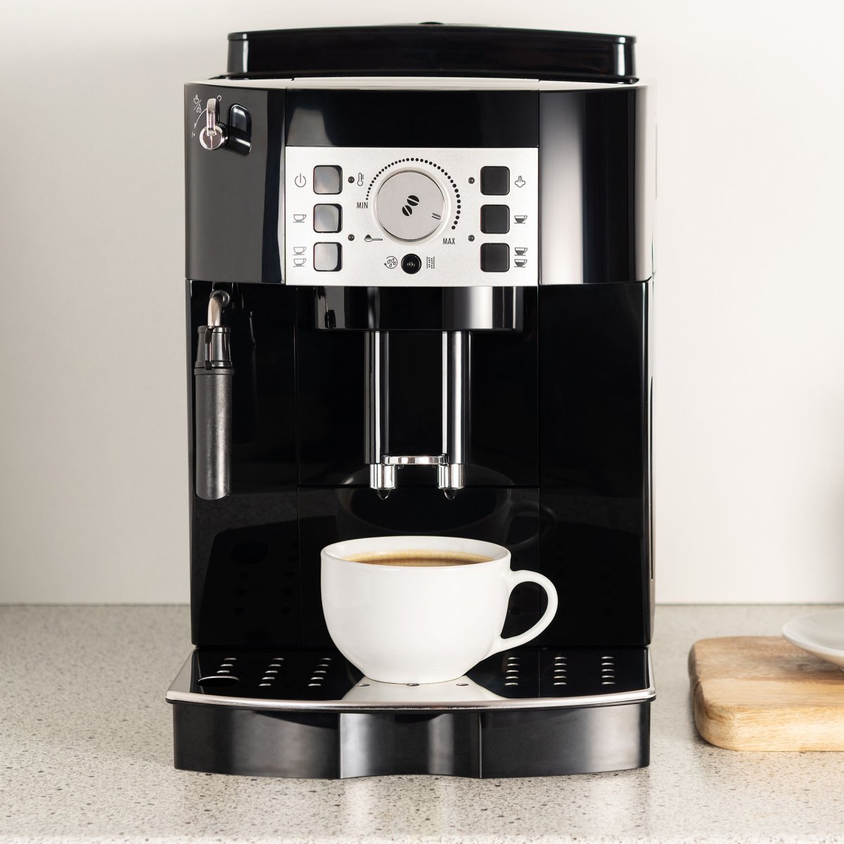 black modern coffee maker on countertop beside wall with freshly brewed cup of coffee