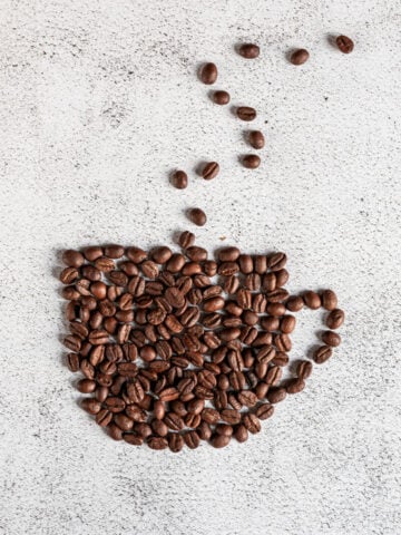 coffee beans shaped into a steaming cup of coffee on white background