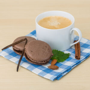 coffee in white ceramic mug beside chocolate macaroons on blue handkerchief