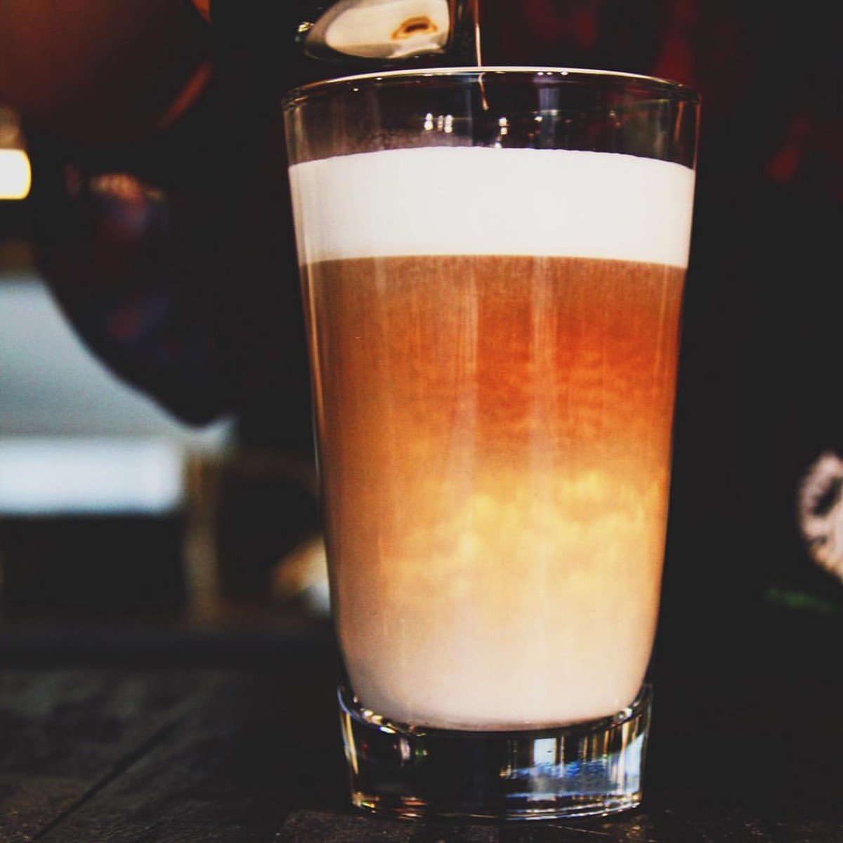 cup of freshly made hot starbucks latte macchiato in clear glass