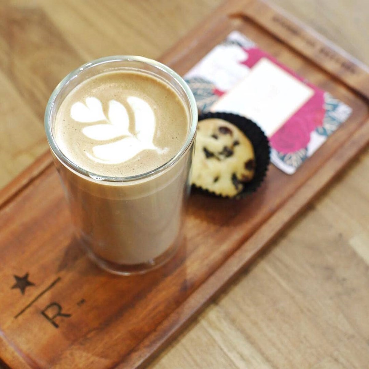cup of hot starbucks reserve latte beside muffin on wooden tray