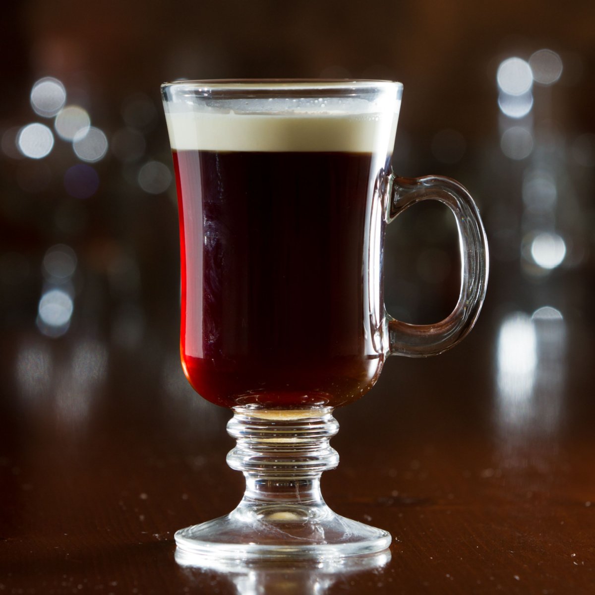 freshly made irish coffee in glass mug heavy cream floating on top of coffee