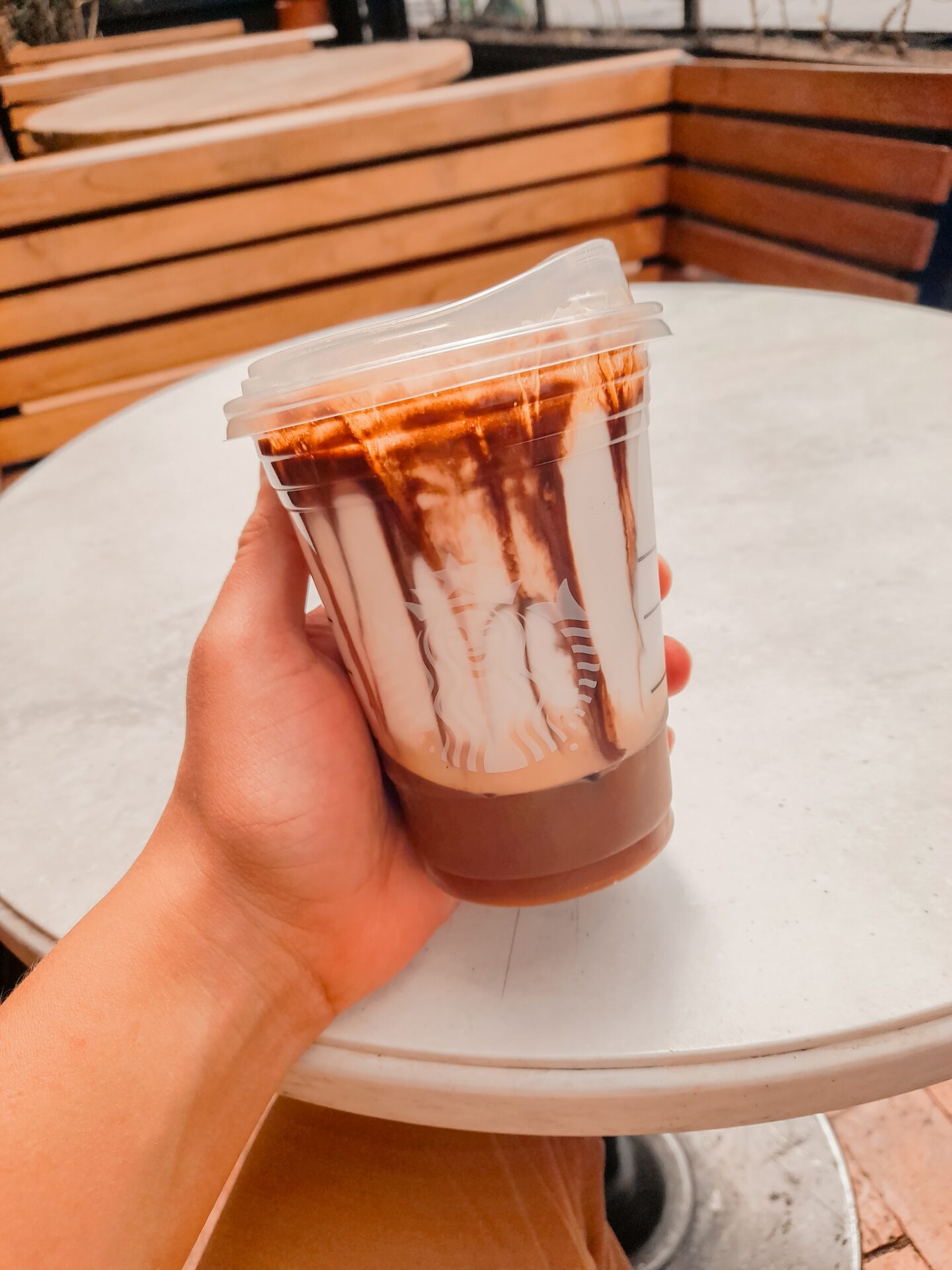 hand holding starbucks iced shaken espresso with milk in clear disposable cup on white table