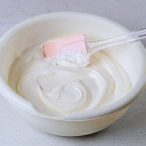 homeamde whipped cream in white bowl with pink rubber spatula